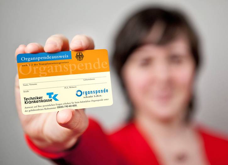 Eine Frau hält einen Organspendeausweis in das Bild