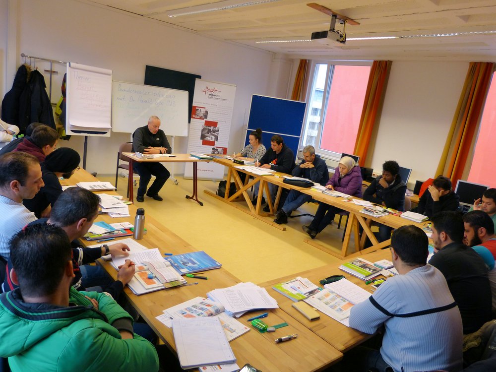 Dr. Harald Terpe liest Teilnehmerinnen und Teilnehmern eines Integrationskurses von Migra e.V. vor.